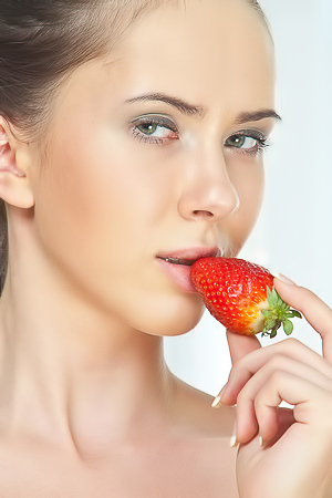 A brunette is eating some strawberries